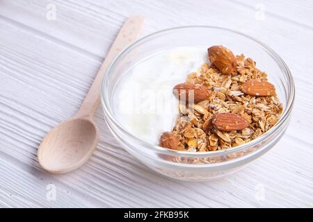 Glasschüssel mit griechischem Joghurt und gemischten Nüssen. Gesunde Sportarten vegetarische eiweißreiche Ernährung, hausgemachtes Müsli-Frühstück mit Milch, Honig, Mandel, Cashew, Stockfoto