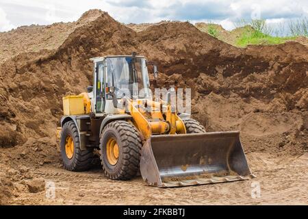 Weißrussland, Minsk - 28. Mai 2020: Bulldozer oder Traktor industrielle schwere Maschine auf einer Baustelle vor dem Hintergrund eines großen Haufen Sandmatte Stockfoto