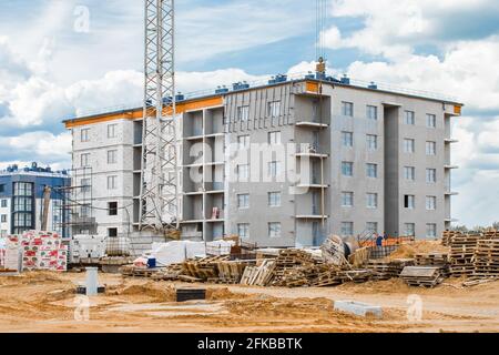 Weißrussland, Minsk - 28. Mai 2020: Baustelle mit einem Haufen alter Holzpaletten. Bau, Außenansicht eines neuen modernen Stadthauses. Stockfoto