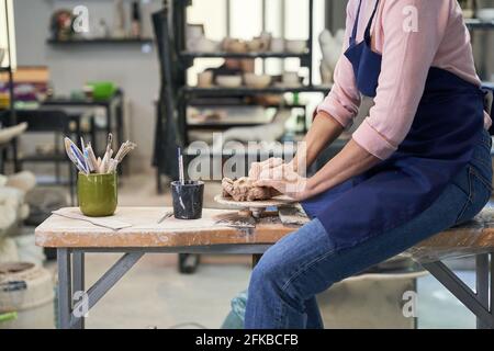 Handgefertigt. Ausgeschnittene Aufnahme einer reifen Frau in der Schürze, die Ton-Keramik in der Töpferwerkstatt erstellt Stockfoto