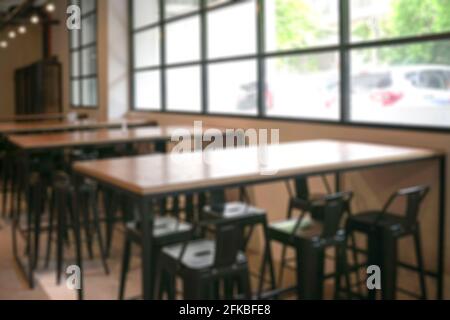 Leere Cafetaria mit Holztischen und Hochstühlen und Fenstern mit Blick nach draußen. Unschärfe-Unschärfe. Stockfoto