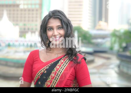 Porträt einer schönen und lächelnden Inderin mit rotem Saree. Außenumgebung. Stockfoto