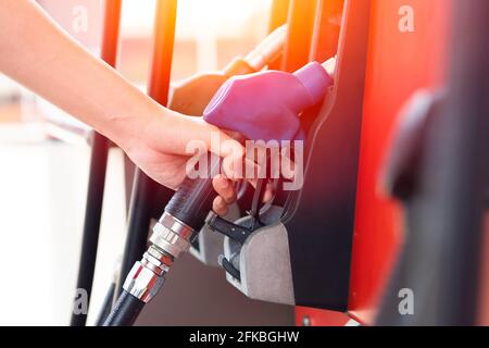 Die Hand des Arbeiters an der Tankstelle handhabt die Kraftstoffdüse am Kraftstoff Zapfsäulen zum Befüllen von Benzin im Automotor Stockfoto