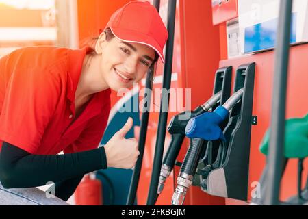 Die Angestellten der Tankstelle humpeln an der Zapfpistole Spender glücklich Service arbeiten füllen Autos Benzin Stockfoto