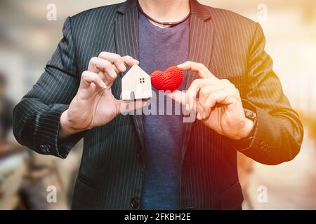 Mann Hand hält kleine Haus und hart Zeichen für Ich liebe das Hotel- oder Geschäftsunterkunft-Service-Konzept Stockfoto