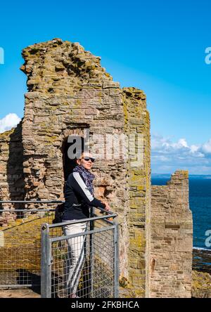 East Lothian, Schottland, Vereinigtes Königreich, 30. April 2021. Historische Umgebung Schottland mittelalterliche Schlösser werden wieder eröffnet: Die ersten Besucher kommen an einem kühlen sonnigen Morgen an buchbaren Stundentagen an, um die Ruinen von Tantallon Castle zu besuchen, da HES im letzten Jahr zum zweiten Mal im ganzen Land wieder Stätten eröffnet. Im Bild: Audrey Opdycke-Barnes genießt die Aussicht auf die Spitze der Zinnen Stockfoto