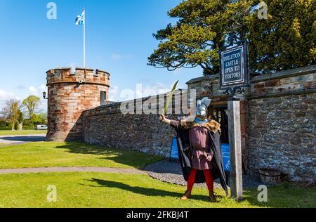 East Lothian, Schottland, Großbritannien, 30. April 2021. Historisches Umfeld Schottland mittelalterliche Burgen wieder geöffnet: Die ersten Besucher kommen an einem kühlen, sonnigen Morgen an buchbaren Stundenabenden für einen Besuch der Ruinen von Dirleton Castle, während HES im letzten Jahr zum zweiten Mal im ganzen Land Sehenswürdigkeiten wiedereröffnet. Im Bild: Andrew Spratt, Wächter, begrüßt die Besucher in passender mittelalterlicher Tracht Stockfoto