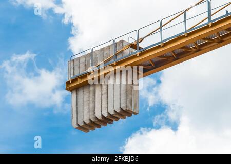 Ein Gegengewicht von Betonblöcken auf dem Heck eines Turmkrans Industrieausrüstung gegen einen blauen Himmel. Nahaufnahme. Stockfoto