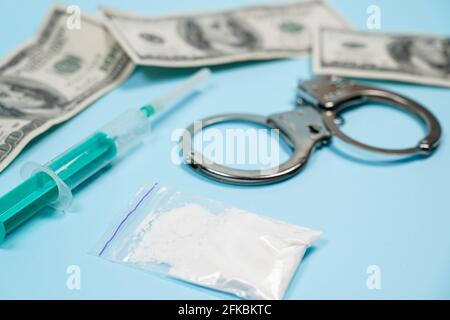 Ein Beutel mit Drogen, US-Dollar und Handschellen auf den Tisch. Konzept - Strafen für den Besitz von Suchtstoffen. Kopieren spase, spase für Text. Stockfoto