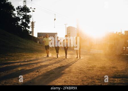 Männliche und weibliche Athleten laufen an sonnigen Tagen an Land Stockfoto