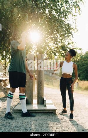 Sportler und Sportlerin trainieren mit Widerstandsband im Park Sonniger Tag Stockfoto