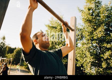 Männlicher Athlet, der im Park an der Affenbar trainiert Stockfoto