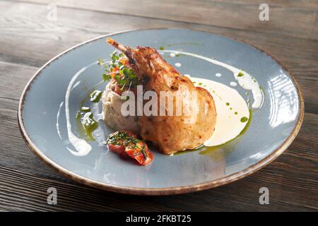 Seitenansicht des saftig gerösteten bbq Hähnchenschenkels, serviert mit Kartoffelpüree und Pilzen, Kirschtomaten, dekoriert mit frischen grünen Sprossen, saurer Creme und Stockfoto