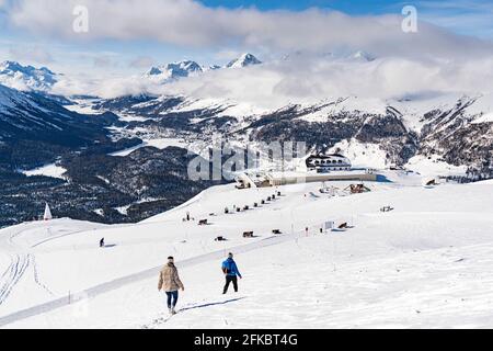 Zwei Wanderer, die auf verschneiten Hängen zur Standseilbahn Muottas Muragl, Samedan, Engadin, Graubünden, Schweiz, Europa Stockfoto