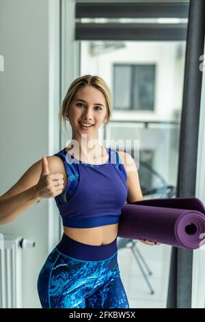 Porträt einer sportlichen Frau, Yoga, Pilates oder anderer Fitnesstrainerin, Blick auf die Kamera, attraktive erfolgreiche Trainerin in Sportswear, grau br Stockfoto