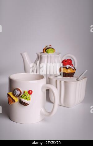 Weißes Geschirr zum Teetrinken. Das Dekor auf den Speisen ist in Form von Süßigkeiten. Tasse, Zuckerdose und Teekannen. Guten Morgen Stockfoto