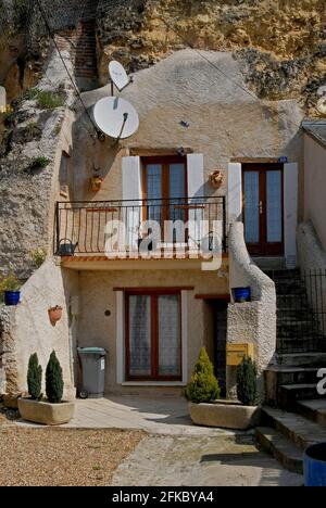 Die Besitzer dieser alten Höhlenwohnung im Loire-Tal, die in eine weiche Kalksteinklippe in der Rue Victor Hugo in Amboise, Centre-Val de Loire, Frankreich, geschnitten wurde, haben viel getan, um sie zu modernisieren – darunter zwei Satellitenschüsseln in die façade. Obwohl einige der Tausenden Höhlen an der Loire inzwischen stillstehen und verkommen, hat eine neue Welle des Interesses an der Lebensweise der Troglodyten andere zu Sommerhäusern, Ferienhäusern, Weinkellern, Pilzfarmen, Museen und Restaurants veranlasst. Stockfoto