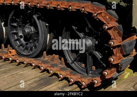 Spinnennetze glitzern im starken Sonnenlicht gegen die schwarz lackierten Räder und die verrostete, gummierte Strecke eines FV180 Combat Engineer Tractor (CET) der britischen Armee, einem 17.5 Tonnen schweren amphibischen gepanzerten Erdbeweger oder Bulldozer, der gebaut wurde, um Hindernisse zu beseitigen, Gruben zu graben, Barrieren vorzubereiten und gestrandete Fahrzeuge zu retten. Es diente im Irak während des ersten Golfkrieges von 1991 und wird jetzt mit anderen militärischen Geräten in Monmouth, Monmouthshire, Wales, Großbritannien, vor dem Great Castle House, Hauptquartier und Regimentsmuseum der Royal Monmouthshire Royal Engineers (Miliz) ausgestellt. Stockfoto