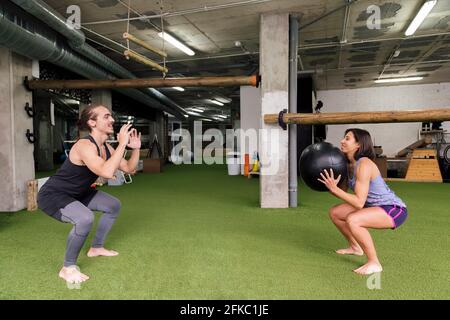 Männliche und weibliche Athleten trainieren gemeinsam in der Turnhalle und werfen einen gewichteten Ball aufeinander, ein aktives und sportliches Lifestyle-Konzept Stockfoto