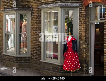 Rotes Kleid einer Frau aus den 1950er Jahren auf einer Schaufensterpuppe vor einem altmodischen Bekleidungsgeschäft in der Harbour Street, Whitstable, Kent, Großbritannien Stockfoto