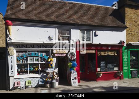Farbenfrohe Geschäfte an einem hellen Morgen im April in der Harbour Street, Whitstable, Großbritannien Stockfoto