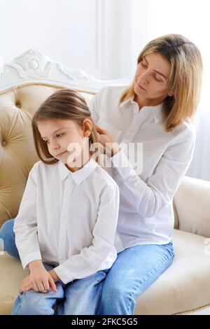 Mama richtet die Haare ihrer Tochter auf. Eltern und Kinder. Familien Stockfoto