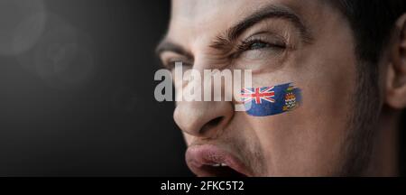 Ein schreiender Mann mit dem Bild der Nationalflagge der Cayman-Inseln auf seinem Gesicht Stockfoto