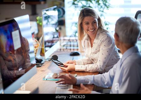 Junge fröhliche Frau, die von einer älteren Partnerin betreut wird Das Büro Stockfoto