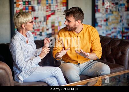 Senior-Partnerin als Mentorin für einen fröhlichen Geschäftsmann im Büro Stockfoto