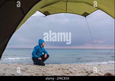 Junger Mann in der Nähe des Campingzelts, der die Aussicht betrachtet. Stockfoto