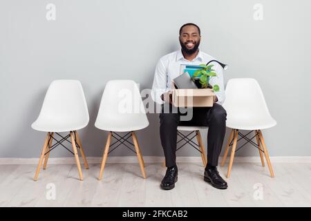 In voller Länge Körpergröße Foto von lächelnden Mann wartet auf Interview, um eine Arbeitsbox mit Habseligkeiten fertig zu machen Zu arbeiten Stockfoto