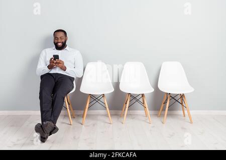 In voller Länge Körpergröße Foto von lächelnden Mann wartet auf Interview mit Smartphone tragen weißes Hemd formelle Kleidung Stockfoto