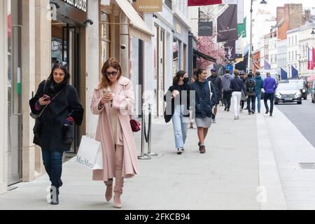 London, Großbritannien, 30. April 2021: Selbst an einem Freitagmorgen ziehen die Luxusboutiquen der Bond Street treue Kunden an, die bereit sind, sich für ein sozial distanziertes Einkaufserlebnis anzustellen und mit einigen Käufen von Designermarken nach Hause zu gehen. Anna Watson/Alamy Live News Stockfoto