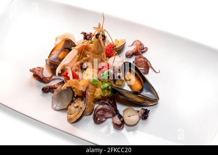 Meeresfrüchte und Schalentiere mit Cous Cous, buntes Gericht mit Scampi, Muscheln, Venusmuscheln, Babykrake und rotem Kaviar Stockfoto