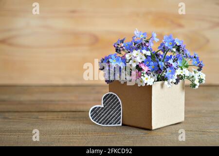 Vatertagskarte. Vergiss mich nicht Blumen in Geschenkbox auf Holzhintergrund mit Kopierraum angeordnet Stockfoto