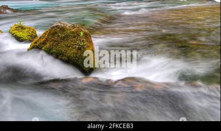 Moos bedeckte Felsbrocken in einem Fluss Stockfoto