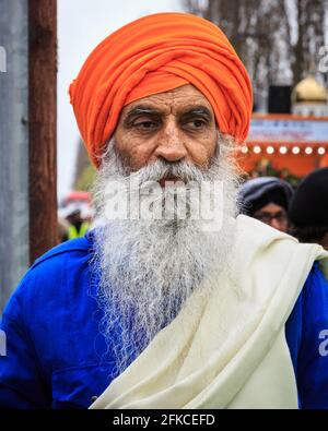 Porträt Sikh-Mann in orangefarbenem Turban (dastar) und Bart in Vaisakhi, Southall, London Stockfoto