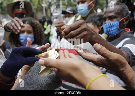 Caracas, Venezuela. April 2021. Eine Person, die zwei verschiedene Handschuhe trägt, verteilt Bilder des venezolanischen Arztes Juan Gregorio Hernandez, des „Arztes der Armen“, vor der Kirche, in der Hernandez selig gesprochen wird. Kredit: Jesus Vargas/dpa - ACHTUNG: Nur für redaktionellen Gebrauch und nur mit vollständiger Erwähnung des oben genannten credit/dpa/Alamy Live News Stockfoto