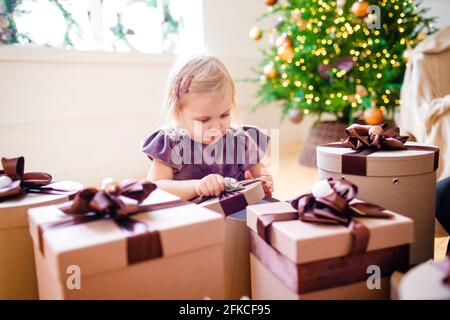 Kleine blonde Mädchen von Weihnachtsgeschenken umgeben. Stockfoto