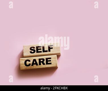 Selbstpflege Worte auf Holzklötze gedruckt, Selbstbehandlung Konzept, rosa Hintergrund Stockfoto