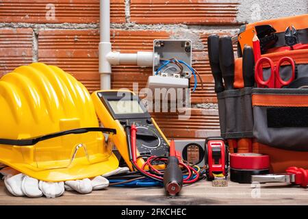 Werkzeugtasche, Werkzeuge und Arbeitsmittel für Elektriker auf einer hölzernen Werkbank. Bauindustrie. Stockfoto