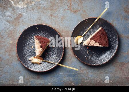 Zwei Stück Schokoladenkuchen auf schwarzen Tellern, Draufsicht. Stockfoto