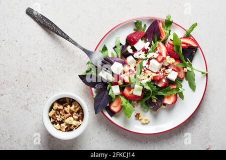 Salat mit Erdbeeren, Rucola, Basilikum und Käse. Stockfoto