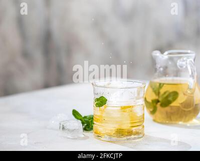 Sommer-Eistee mit frischer Minze auf hellem Tisch. Konzept „Food in Motion“. Cocktail mit kalten Getränken im Sommer. Speicherplatz kopieren Stockfoto