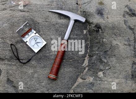 Geologen Kompass auf den Steinen mit Hammer. Konzept der Geologie-Wissenschaft. Der Hammer und die Werkzeuge des Geologen sind auf einem Stein angelegt Stockfoto