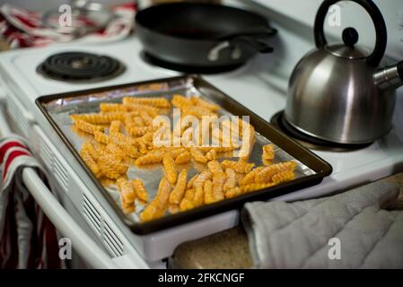 Ein mit Folie ausgekleidete Backblech, bedeckt mit gefrorenen pommes Frites, wartet darauf, in den Ofen zu gehen Stockfoto