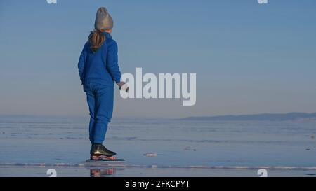 Das Mädchen trainiert auf Eisschnelllauf. Das Kind Schlittschuhe im Winter in blauem Sportswear-Anzug, Sportbrille. Kinder Eisschnelllauf Sport. Stockfoto