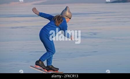 Das Mädchen trainiert auf Eisschnelllauf. Das Kind Schlittschuhe im Winter in blauem Sportswear-Anzug, Sportbrille. Kinder Eisschnelllauf Sport. Stockfoto