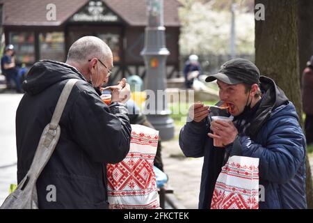 Lviv, Ukraine. April 2021. Zwei Männer essen am Vorabend des orthodoxen Osterfestes in Lemberg kostenloses Essen der Emmaus-Gemeinschaft für gegenseitige Hilfe.am Vorabend des orthodoxen Osterfestes, das am 2. Mai gefeiert wird, verteilte die Emmaus-Gemeinschaft für gegenseitige Hilfe in Lemberg Osterpakete an Obdachlose und Menschen mit geringem Einkommen. Kredit: SOPA Images Limited/Alamy Live Nachrichten Stockfoto