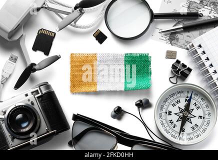 Flagge der Elfenbeinküste und Reisezubehör auf weißem Hintergrund. Stockfoto